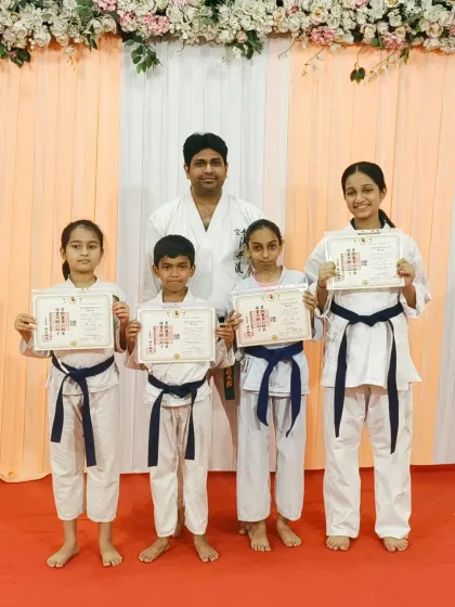 A group of students who have achieved their blue belts, a testament to their consistent training and focus at Rejoice International School.