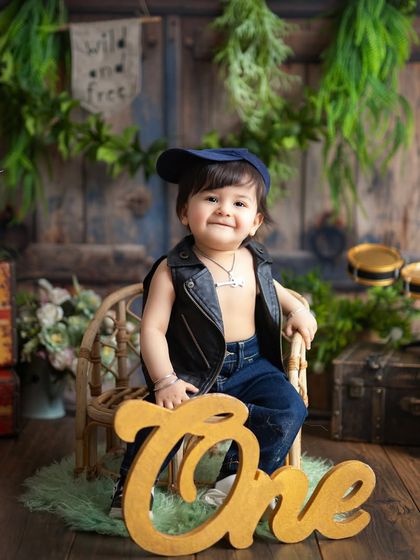 This cool little dude is celebrating his first birthday in style. The 'ONE' sign clearly marks the occasion in this fun, rocker-themed photoshoot.