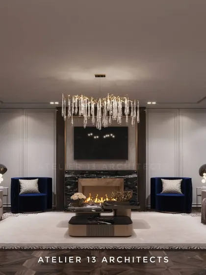 This formal living room is designed for symmetry and elegance, featuring a fireplace flanked by two bold blue armchairs. A cascading crystal chandelier and paneled walls add a layer of classic sophistication to the modern furnishings.