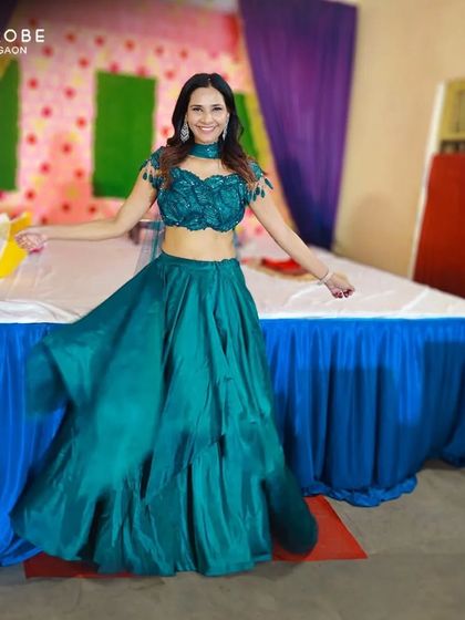 This happy customer looks beautiful in a modern teal lehenga with a unique off-shoulder blouse. It's a fresh and stylish look for any party.