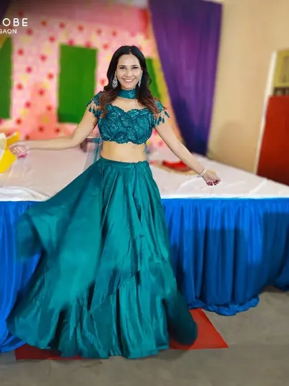 This happy customer looks beautiful in a modern teal lehenga with a unique off-shoulder blouse. It's a fresh and stylish look for any party.