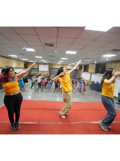 My team on stage, leading the kids in a powerful dance pose. This photo captures the energy and enthusiasm we bring to our community workshops.