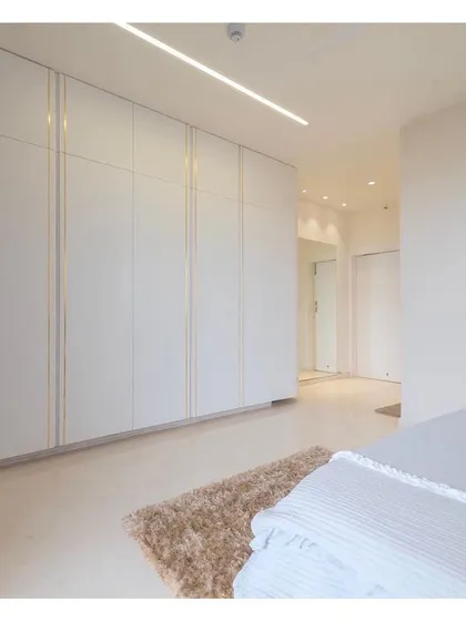 A closer look at the master bedroom's white satin finish cabinets, detailed with subtle brushed brass strips. This small detail adds a touch of elegance and luxury, elevating the minimalist design of the wardrobe.