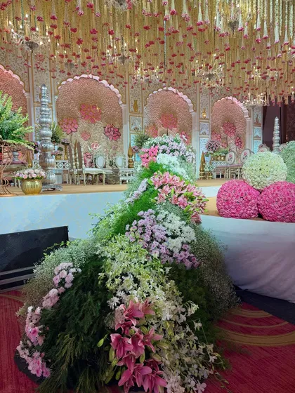 A close-up of the cascading floral arrangements at the edge of the stage, featuring a mix of lilies, roses, and baby's breath for a textured, organic feel.