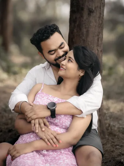 A sweet and happy embrace under a tree. The genuine smiles and loving looks make this a cherished memory.