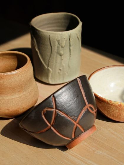 A set of four unique pieces, including a textured mug and a black bowl with sgraffito carving, highlighting the individual styles of our students.