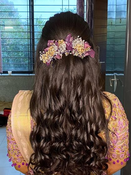 A reception hairstyle with soft curls and a custom floral hairpiece, designed to match the client's outfit.
