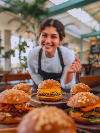 A chef presents a table full of our gourmet burgers, each one crafted with love and the freshest ingredients, like a hug from a friend.