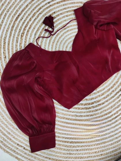 This stunning organza blouse in a deep maroon color adds a touch of drama to any saree.