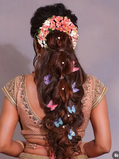 A gorgeous wavy ponytail hairstyle, adorned with a floral crown and delicate butterfly clips. This look is both modern and romantic, ideal for an engagement or reception.