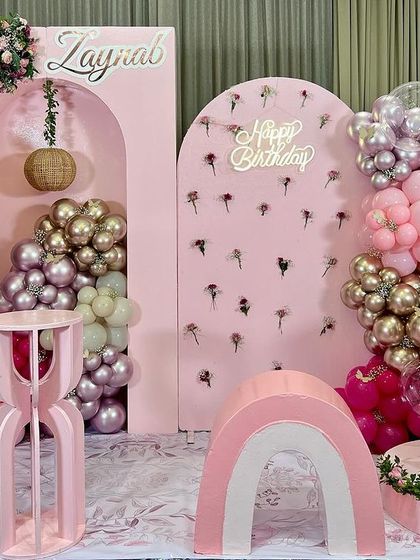 A dreamy hot air balloon theme for Zaynab's first birthday. The all-pink decor includes a large balloon prop, a light-up number '1', and a beautiful wall of flowers, creating a soft and elegant atmosphere.