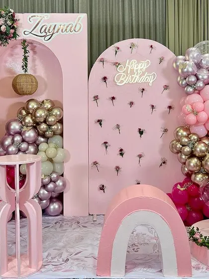 A dreamy hot air balloon theme for Zaynab's first birthday. The all-pink decor includes a large balloon prop, a light-up number '1', and a beautiful wall of flowers, creating a soft and elegant atmosphere.