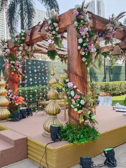Another angle of the rustic-chic wooden mandap, highlighting the beautiful floral arrangements on the pillars and the traditional golden 'kalash' accents.