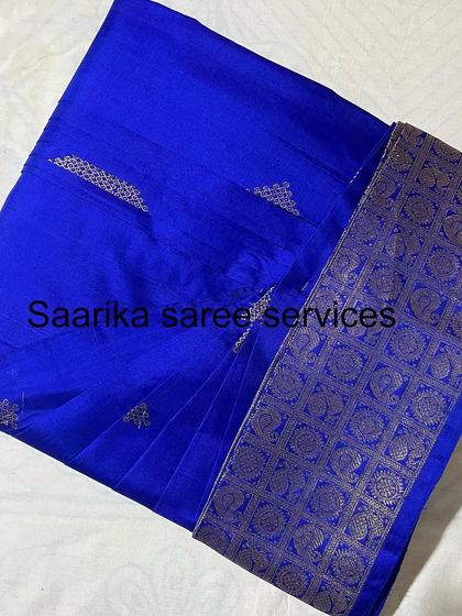 A stunning royal blue saree with a heavy gold border, folded and ready for a grand occasion.