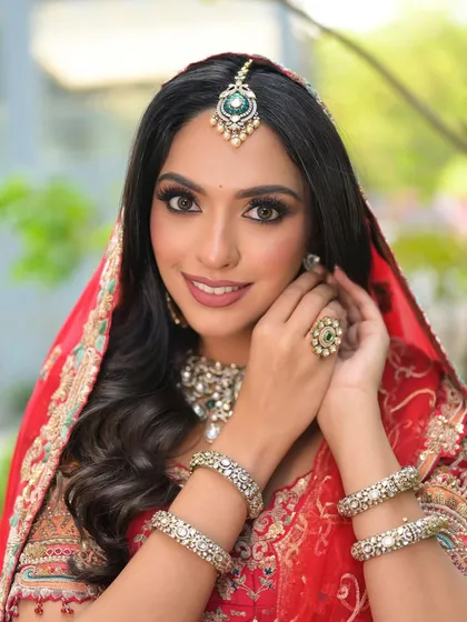 A close-up shot highlighting the flawless base makeup, defined eyes, and the beautiful maang tikka and ring.