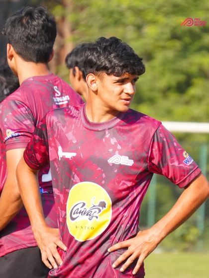 A young player looks on, focused and ready to contribute to the team's effort.