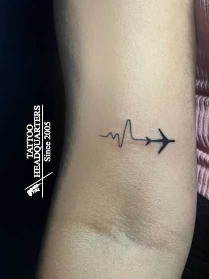 A minimalist tattoo of a heartbeat line that turns into an airplane, perfect for someone whose heart belongs to travel.