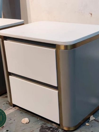 A pair of modern, two-drawer nightstands in our workshop. The design features a clean white finish with a gold-finished metal frame, blending minimalism with a touch of glamour.
