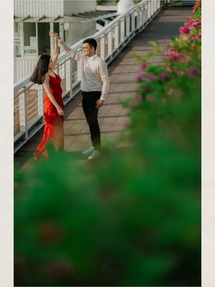 A playful moment of a couple dancing on a bridge, framed by lush greenery. This shot combines urban elements with natural beauty for a unique pre-wedding photo.