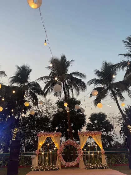 A beautiful reception stage set against a backdrop of palm trees and the evening sky. The floral hoop and hanging lights create a simple yet romantic focal point.