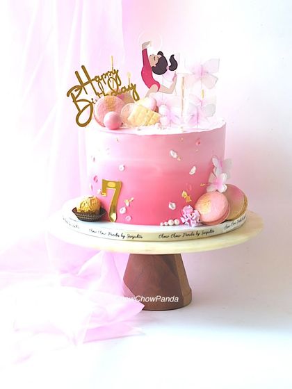 A cake for a young gymnast, celebrating her 7th birthday. This pink ombre cake is decorated with a gymnast topper, macarons, and delicate butterfly details.