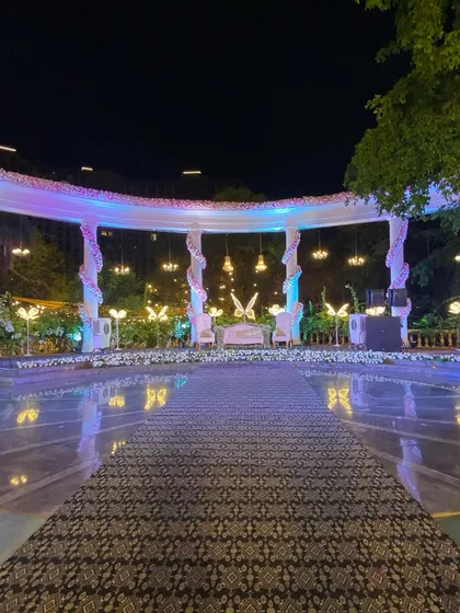This elegant reception stage, set by a poolside, features a grand white structure with hanging chandeliers and glowing butterfly motifs. We designed it to be a magical focal point for the couple's special evening.