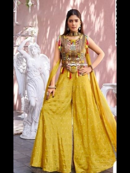 A full-length view of the mustard yellow palazzo set, showing the attached dupatta-style drapes that add a flowy, elegant element to the modern silhouette.