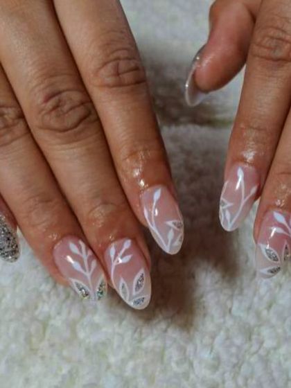 A delicate design with white leaf patterns and a silver glitter accent nail. This is a lovely and elegant look, perfect for a winter theme.