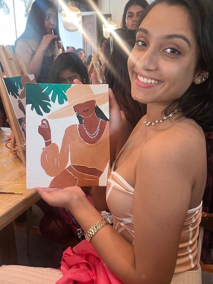 A smiling participant with her stylish summer portrait painting. The workshops are a great way to express your personal style through art.