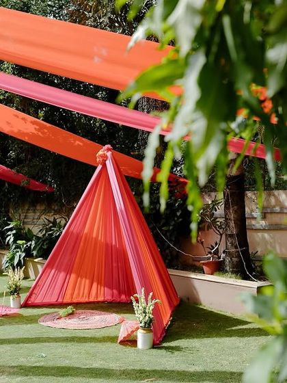 A small, tent-like structure made from colorful drapes in the garden. This was a cozy little photo corner we created as part of the larger Haldi decor, perfect for guests to take pictures.