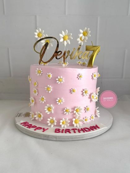 A sweet and cheerful pink cake covered in adorable little fondant daisies.