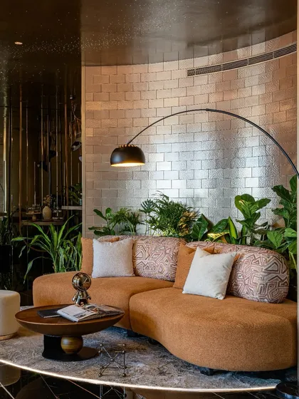 This is our vision for the modern workplace: The Midas Lounge, an office with no workstations. We used a curved sofa, metallic-finish brick tiles, and lush biophilic elements to design a space for connection and creativity, not just work.
