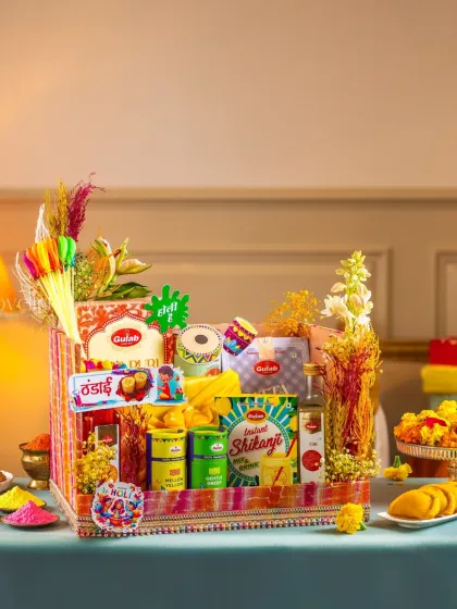 A beautifully arranged Holi gift basket with traditional sweets, thandai mix, and herbal colors.