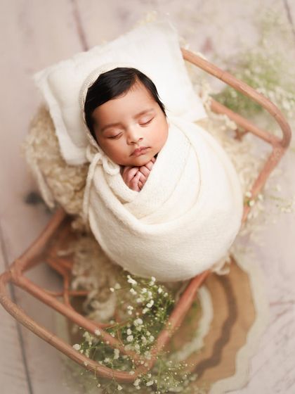 Capturing new beginnings is what I love most. This baby is peacefully asleep in a white wrap, nestled in a prop surrounded by delicate baby's breath flowers.