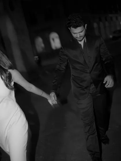 A motion-blurred black and white shot of a couple walking at night, capturing the energy and romance of a city evening.