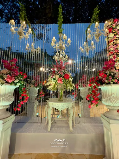 An elegant side setup on the main stage, featuring crystal chandeliers, lush floral arrangements in white urns, and a mirrored backdrop for added glamour.