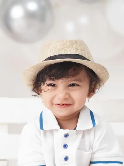 A charming close-up of the little cricketer, capturing his sweet, shy smile and stylish hat.