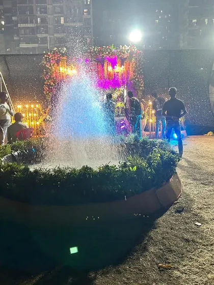 A unique water fountain feature we incorporated into an outdoor wedding venue. The fountain is lit with blue light and surrounded by greenery, adding a dynamic and refreshing element to the decor.