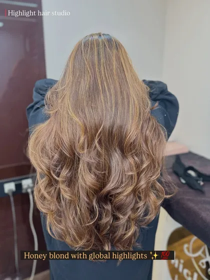 We are obsessed with this honey blonde look. We combined a global color base with carefully placed highlights to create this warm, multi-dimensional result, finished with bouncy curls.