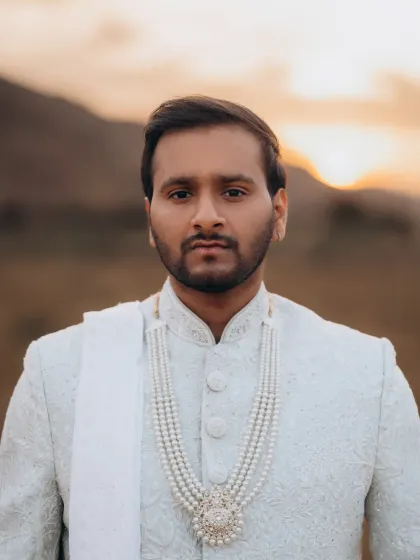 A confident close-up of the groom. The warm sunset light and the mountain backdrop add a dramatic and romantic touch to this portrait.