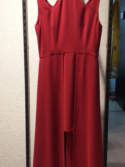 A minimalist red gown with interesting cutout details at the neckline and a high-low hem. This is a modern and understated piece for someone with a contemporary sense of style.