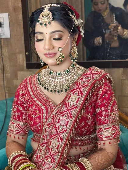 This image captures the serene beauty of a bride with her eyes closed, highlighting the flawless eye makeup and the intricate details of her hair and outfit.