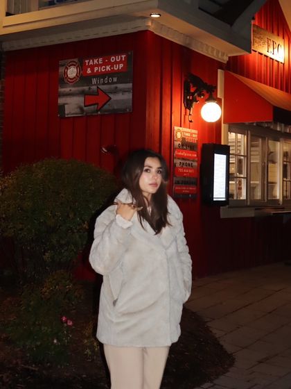 Posing in front of a classic red building in Blue Mountain, adding a pop of color to the night scene.