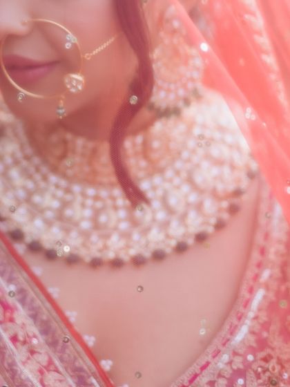 A soft-focus, artistic close-up of a bride's face, focusing on her nose ring and jewelry.
