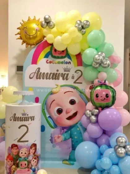 A personalized Cocomelon theme for Amaira's second birthday. This setup features a custom backdrop and plinth with the birthday girl's name and age, surrounded by soft pastel balloons.