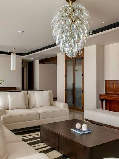 The piano corner in the Parishram residence, where a piece of circular, abstract art hangs above, creating a dedicated space for music and creativity.