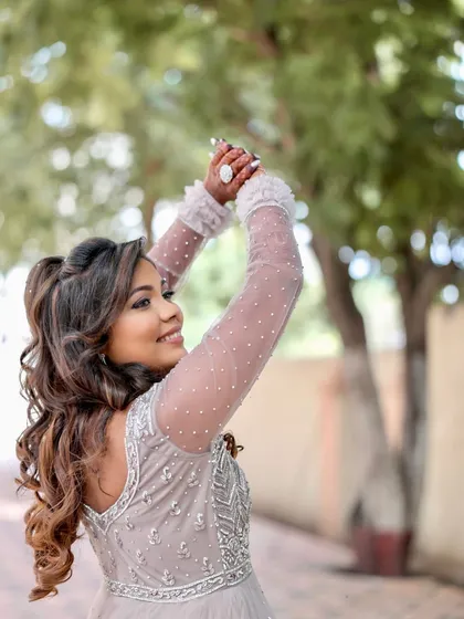 Reception ready in a stunning silver gown. The makeup is soft yet glamorous, with shimmering eyes and beautiful curls, creating a look that is perfect for celebrating the night away.