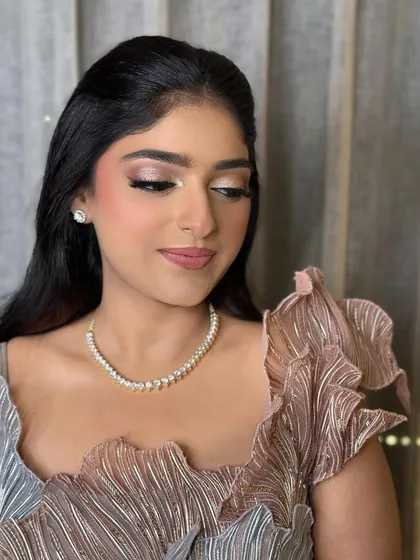 A soft glam look for an engagement. The makeup features shimmery champagne eyeshadow and a pinky-nude lip, complementing her unique pleated gown.