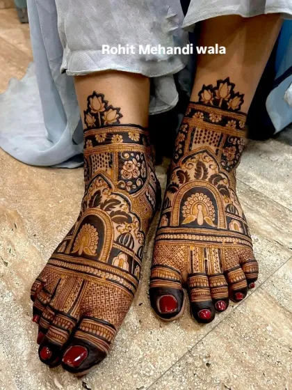 A bold and dark-staining design for the feet. This artwork includes peacock figures inside ornate arches, with a lotus pattern finishing the design at the ankle.