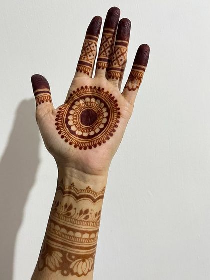 The beautiful, dark stain of a mandala design. The central circle on the palm is surrounded by detailed finger work and a patterned wrist cuff.